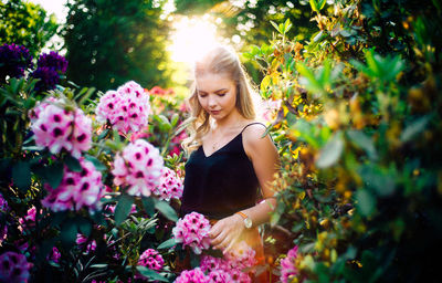 Young woman standing by pink flowering plants at park