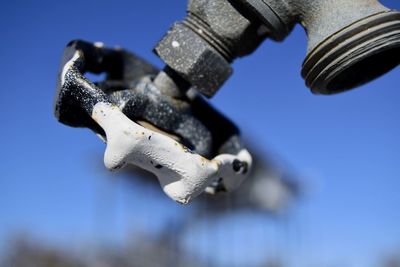 Low angle view of faucet against blue sky