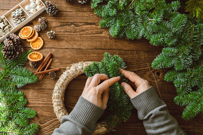 Top view of male hands making a christmas wreath from natural spruce branches