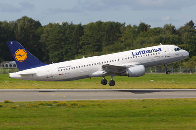 Side view of airplane on airport runway against sky