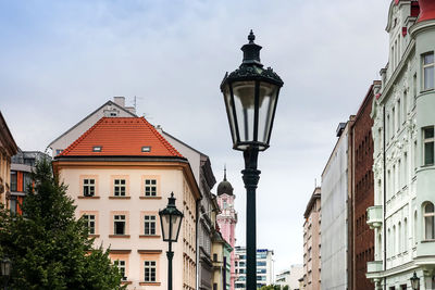 Low angle view of buildings and street lights against sky