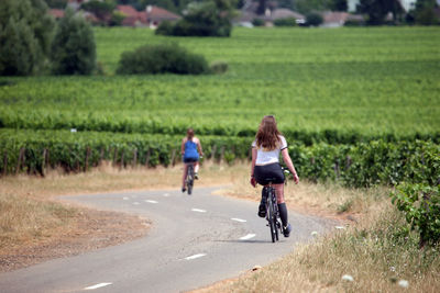 Rear view of women bicycling on country road