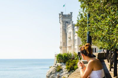 Woman by sea against clear sky