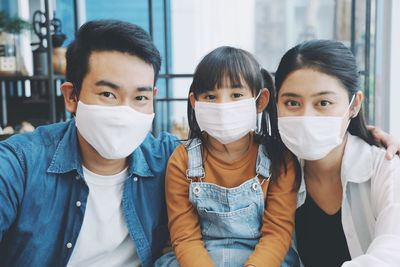 Portrait of smiling family wearing flu mask sitting at home