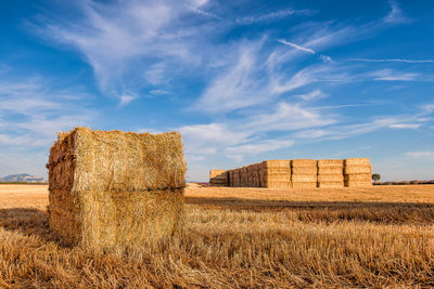 Scenic view of hay bales on a harvested wheat field in provence against dramatic blue sky