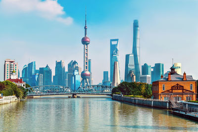 View of buildings by river against sky in city