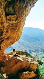 Woman sitting on rock against mountains