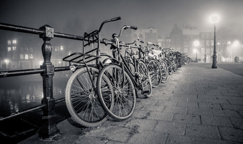 Bicycle parked by railing at night