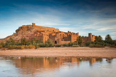Buildings at waterfront against cloudy sky