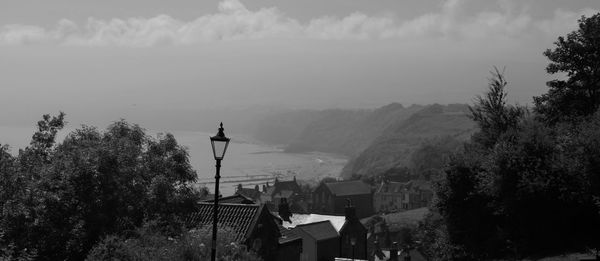 Houses by sea and mountains against sky