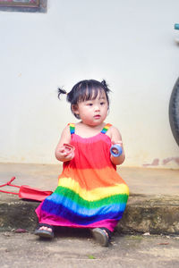 Portrait of cute girl standing against wall