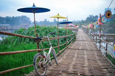 Bicycle on footpath by water against sky