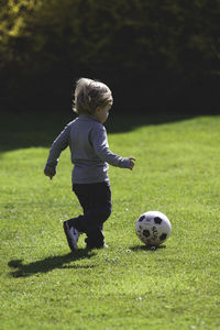 Full length of boy playing soccer on field