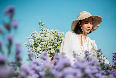 Woman standing by purple flowering plants against sky