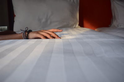 Cropped hand of woman on bed at home
