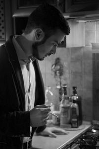 Thoughtful businessman smoking while standing by kitchen counter