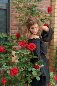 Woman standing by red flowering plants