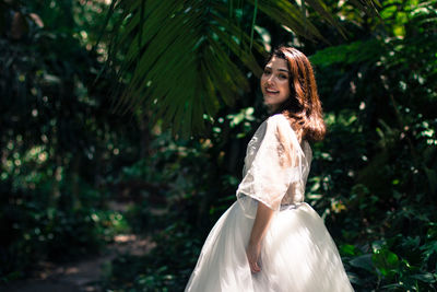 Portrait of smiling woman standing in forest