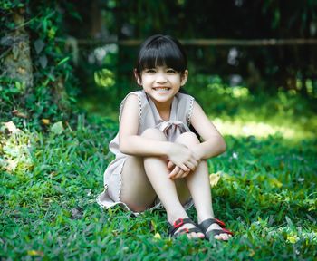 Portrait of smiling girl sitting at public park