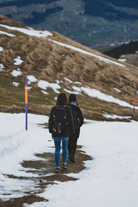 Rear view of people walking on snow covered landscape