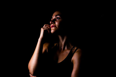 Young woman standing against black background