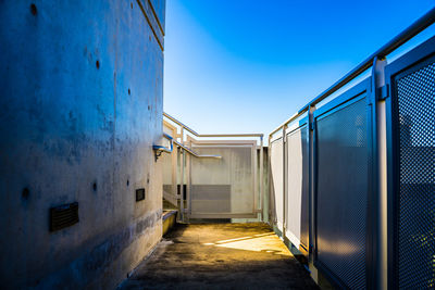 Alley amidst buildings against blue sky