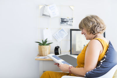 Side view of woman reading book at home