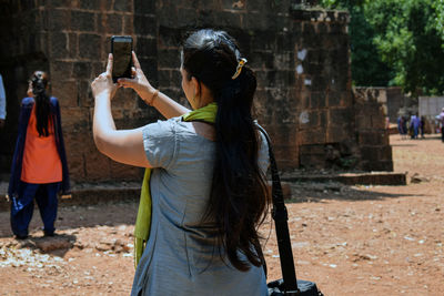 Rear view of woman photographing at camera