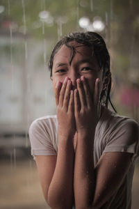 Portrait of girl covering mouth during rainy season