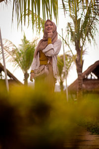 Full length of woman standing on palm tree