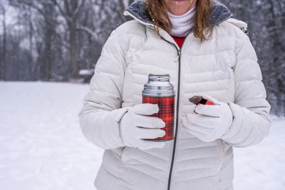 Midsection of woman with umbrella standing in snow