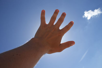 Low angle view of cropped hand against clear sky