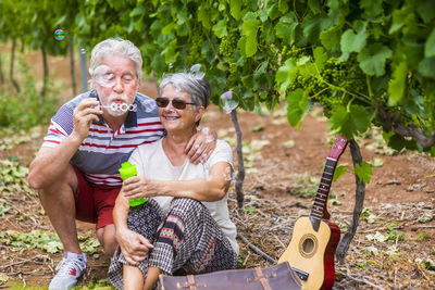 Senior couple sitting on field at vineyard