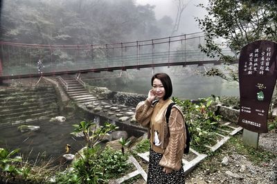 Portrait of woman standing by river at forest