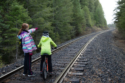 Rear view of people standing on railroad tracks