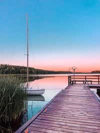 Pier over lake against clear blue sky