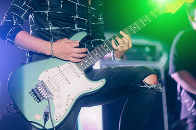 Midsection of musician playing guitar