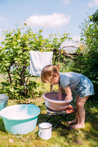 Little preschool girl helps with laundry. child washes clothes in garden