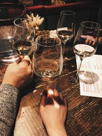 Cropped image of hand holding wine glasses on table at restaurant