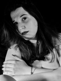 Portrait of beautiful young woman against black background