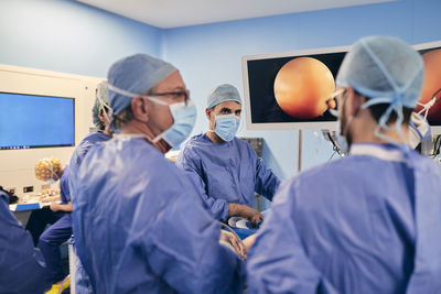 Surgeons wearing face mask having discussion while operating surgery in operation room
