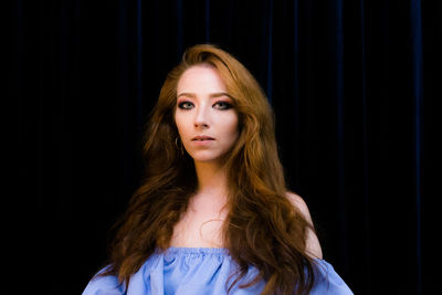 Portrait of young woman with long hair in dark