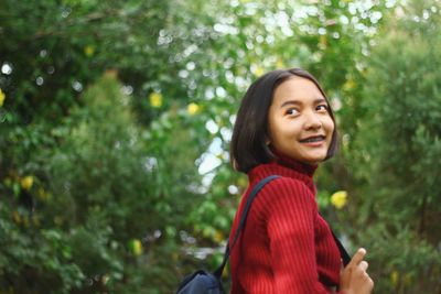 Smiling teenage girl against trees in forest