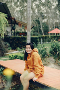 Portrait of young woman standing against trees