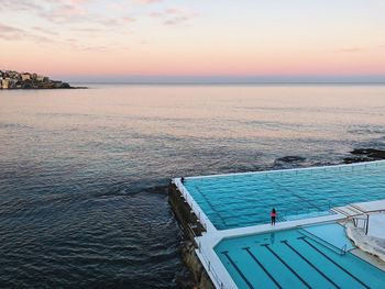 High angle view of swimming pool by sea against sky during sunset