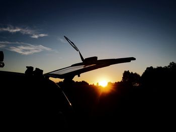 Silhouette of airplane flying against sky during sunset