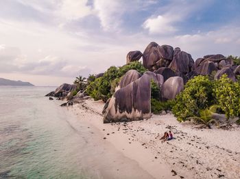 High angle view of couple sitting at beach against cloudy sky