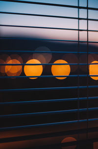 Close-up of illuminated defocused lights seen through window at night