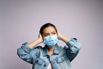 Portrait of young woman standing gesturing against gray background