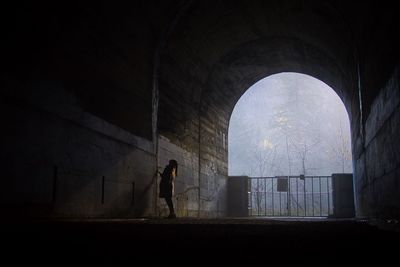 Full length of lonely woman standing in abandoned tunnel